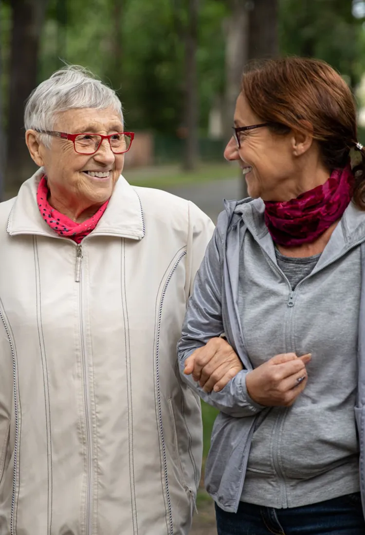 Seniorin spaziert mit Betreuungsperson durch den Park und genießt Bewegung und persönliche Begleitung im Alltag