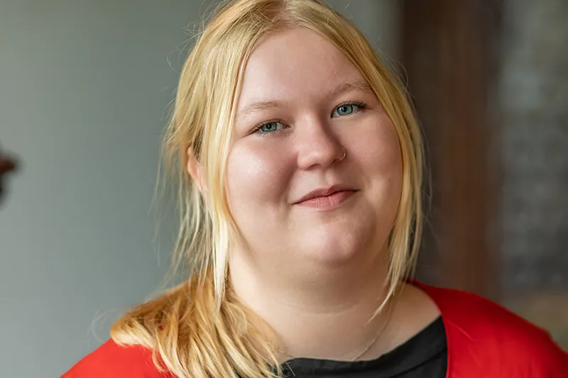 Emily Heydrich lächelt in die Kamera und ist Ansprechpartnerin für die Teamleitung Organisation bei Herzwohl