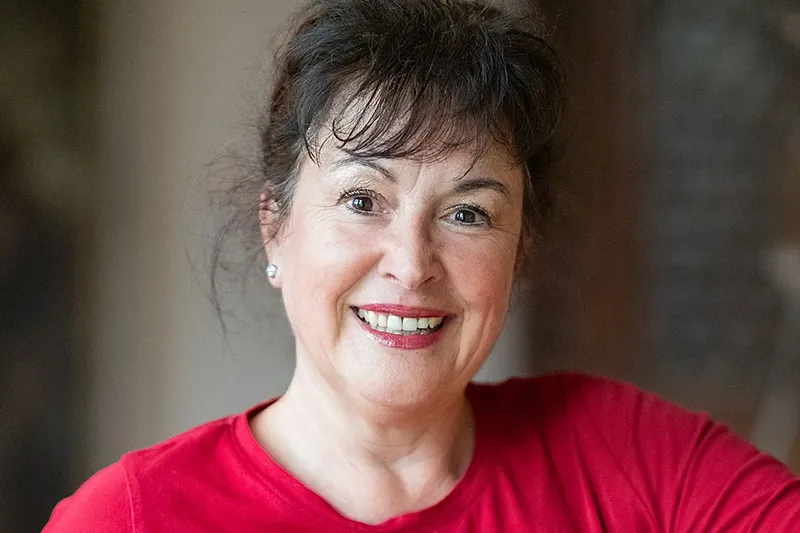 Sabine Blank lächelt in die Kamera und ist Ansprechpartnerin für die Tagespflege bei Herzwohl