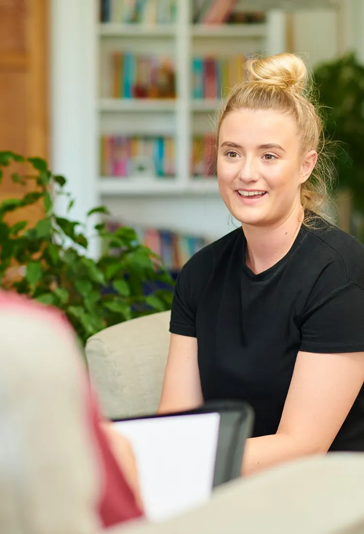 Pflegekraft führt ein einfühlsames Gespräch mit einer Angehörigen und berät zu Entlastung und Pflegeangeboten