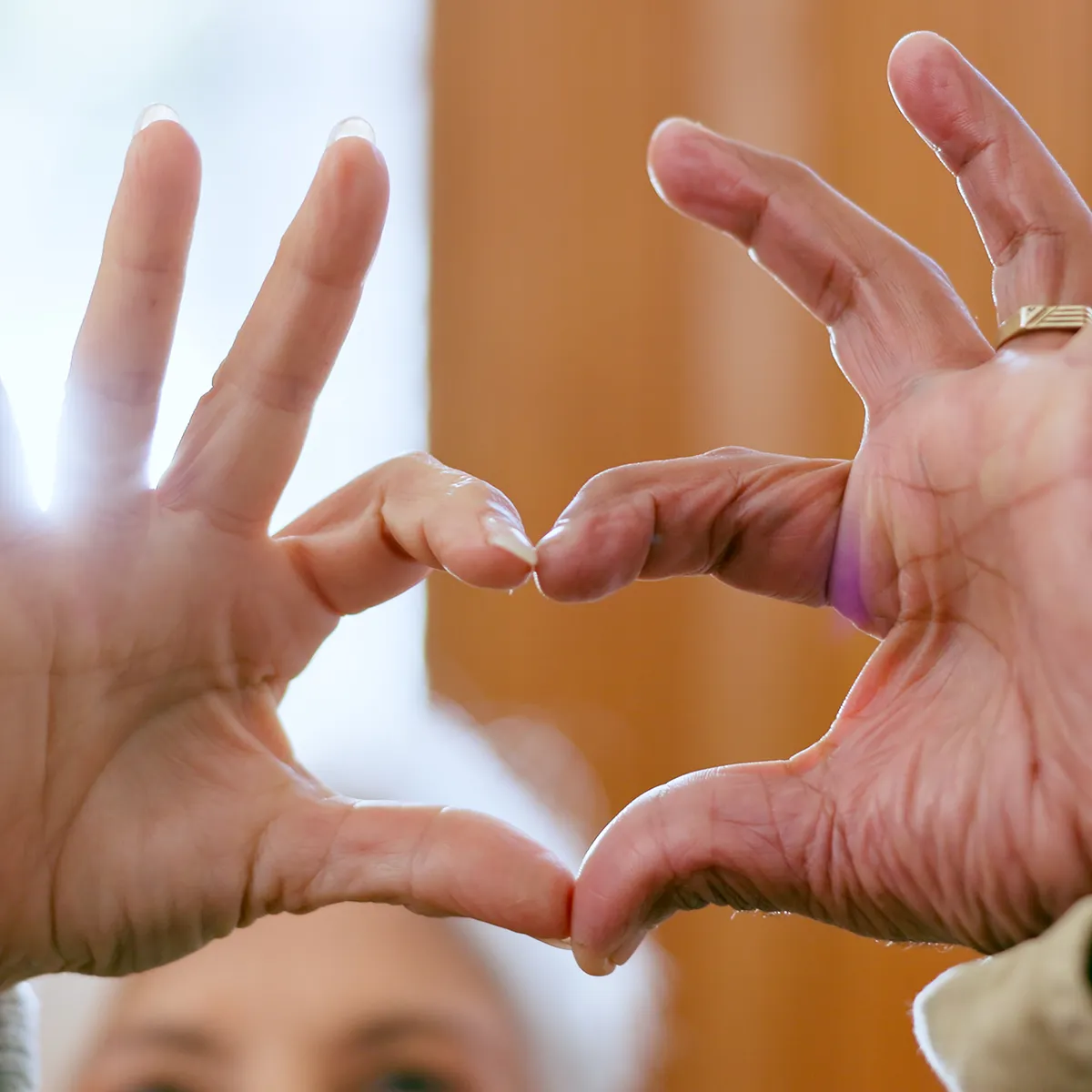 Zwei Hände formen ein Herzsymbol und stehen sinnbildlich für Nähe, Vertrauen und Pflege mit Herz im Alltag