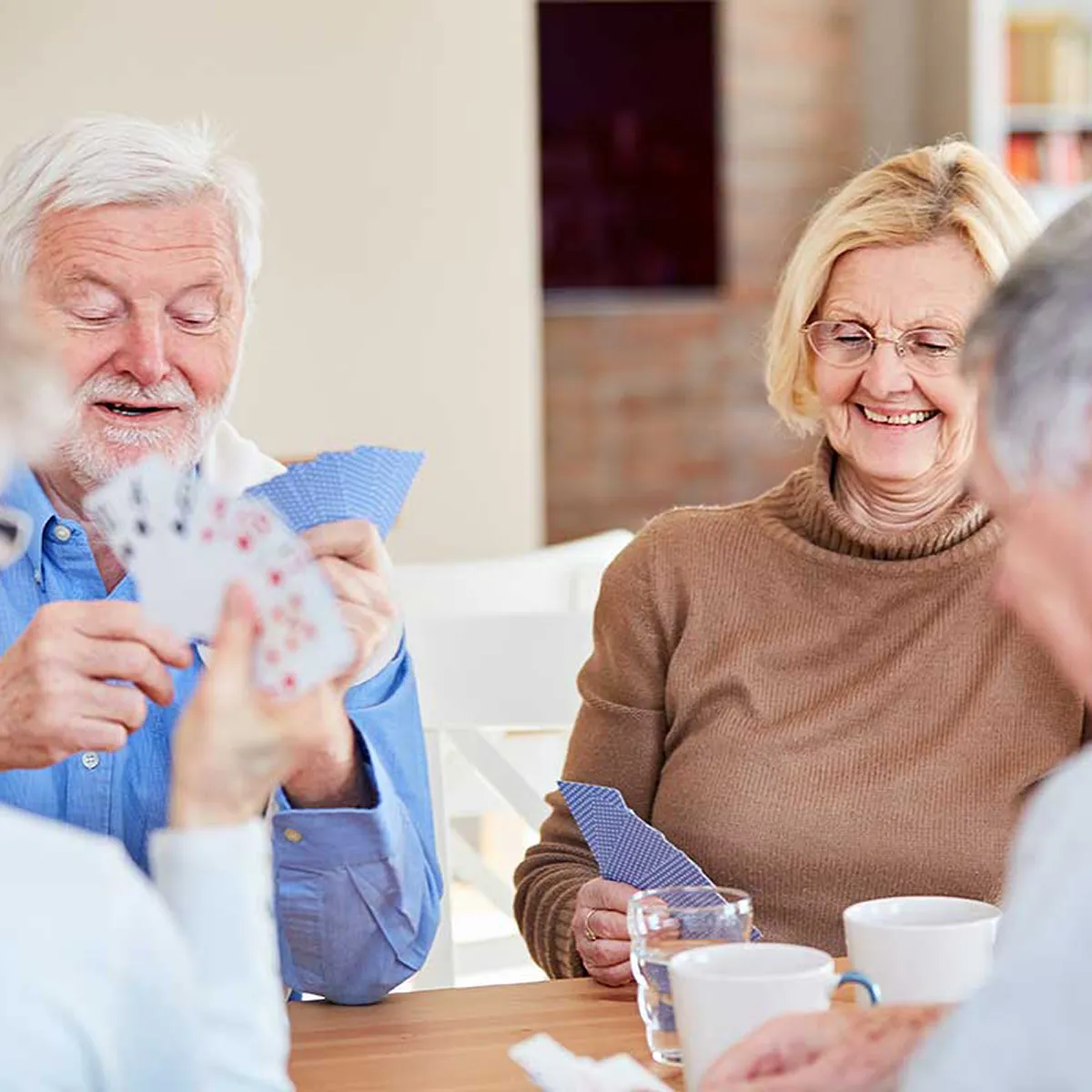 Senioren sitzen gemeinsam am Tisch und spielen Karten in entspannter Atmosphäre der Tagespflege