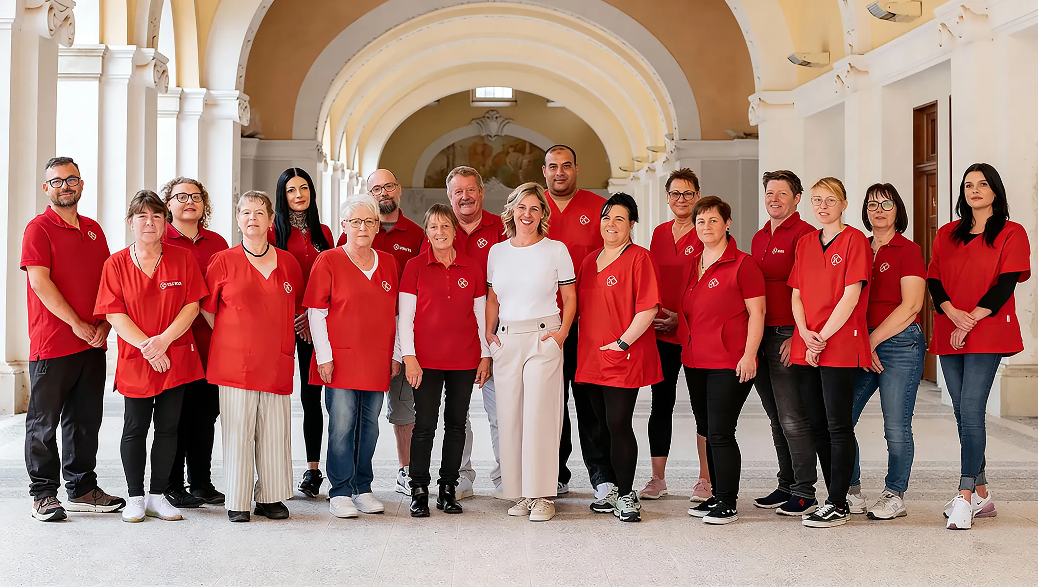 Das Team von Herzwohl steht gemeinsam in einem hellen Gebäude und zeigt Zusammenhalt, Vielfalt und Engagement in der Pflege